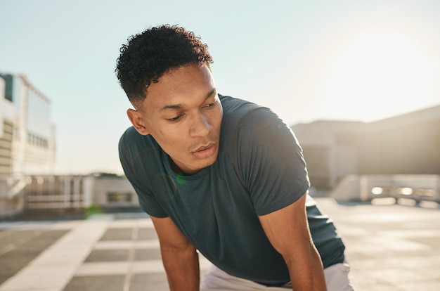 Fitness del corridore e uomo stanco in una città affaticamento dovuto alla corsa, esercizio cardio, allenamento o allenamento Affaticamento respiratorio e atleta sportivo sano che si rilassa o si riposa durante una pausa dall'allenamento della maratona