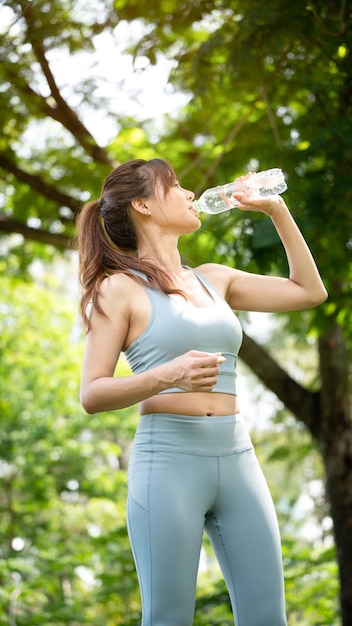 Fitness donna acqua potabile Giovane donna assetata acqua potabile da una bottiglia nel parco estivo Sport