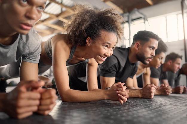 Fitness donna e esercizio di plancia nella palestra di allenamento di gruppo per il benessere stile di vita sano e allenamento Forte giovane e felice atleta ragazza nera e push up a terra con gli amici per la sfida sportiva