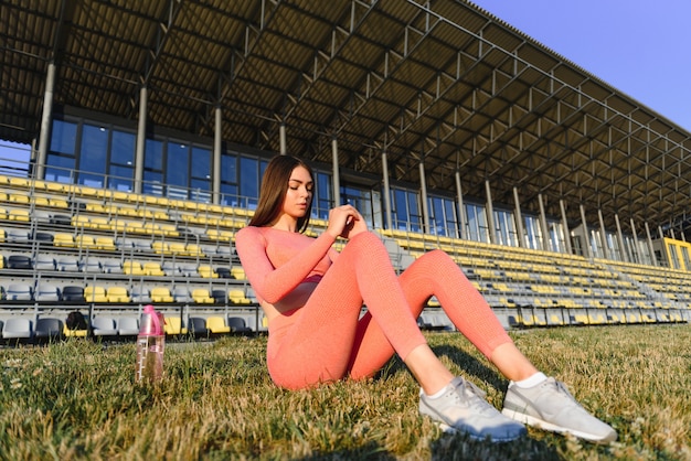 Fitness donna facendo sit up nello stadio lavorando. Ragazza sportiva che esercita gli addominali, all'aperto