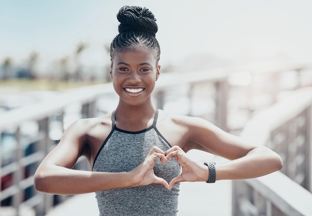 Fitness donna nera e gesto del cuore ritratto per un sano allenamento fisico e allenamento all'aria aperta Felice corridore femminile afroamericano attivo con sorriso e amore forma le mani per il benessere