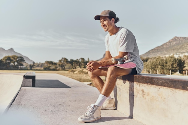 Fitness e ricreazione con lo skateboard con un uomo sportivo seduto su un muro in uno skatepark durante il giorno Allenamento e pattinaggio con un atleta maschio o uno skater che si diverte all'aperto in estate