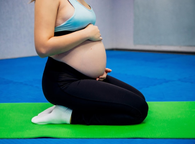 Fitness e stile di vita sano durante la gravidanza Una ragazza incinta con una pancia grande fa sport durante il terzo trimestre Divisa sportiva Sanità In attesa di un bambino