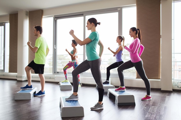 fitness, sport, allenamento, aerobica e concetto di persone - gruppo di persone che si allenano con gli stepper in palestra