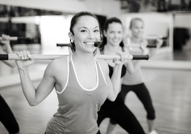 fitness, sport, allenamento, palestra e concetto di stile di vita - allenatore sorridente di fronte al gruppo di persone che si allenano con i bilancieri in palestra