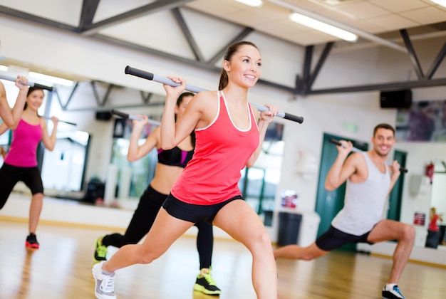 fitness, sport, allenamento, palestra e concetto di stile di vita - gruppo di persone sorridenti che si allenano con i bilancieri in palestra