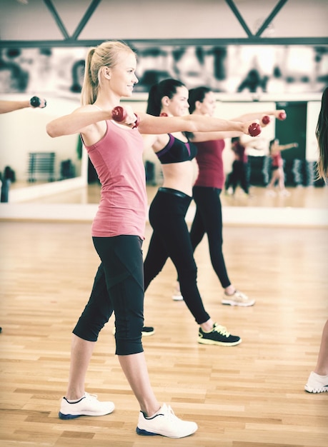 fitness, sport, allenamento, palestra e concetto di stile di vita - gruppo di persone sorridenti che si allenano con i manubri in palestra