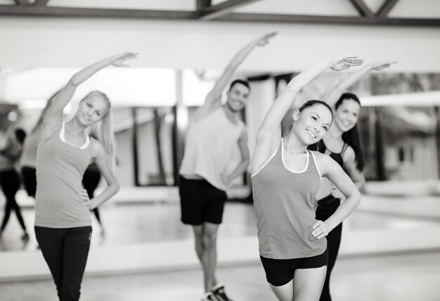 fitness, sport, allenamento, palestra e concetto di stile di vita - gruppo di persone sorridenti che si allungano in palestra