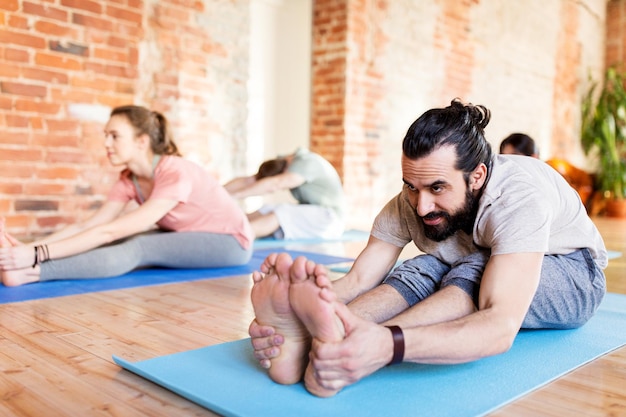 fitness, sport e stile di vita sano concetto - gruppo di persone che fanno yoga seduti in avanti piegato pose su tappetini allo studio