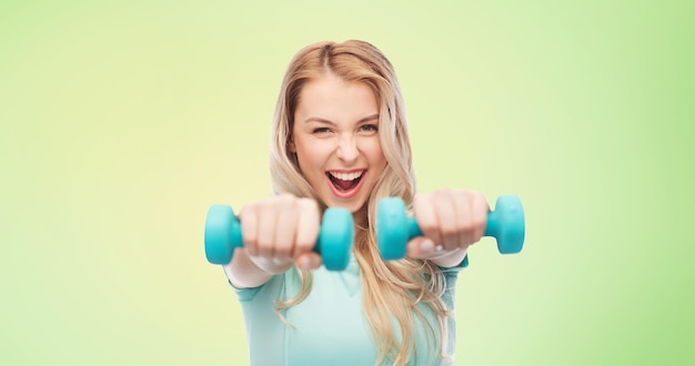fitness, sport, esercizio fisico e concetto di persone - bella donna sportiva sorridente con manubri su sfondo verde naturale