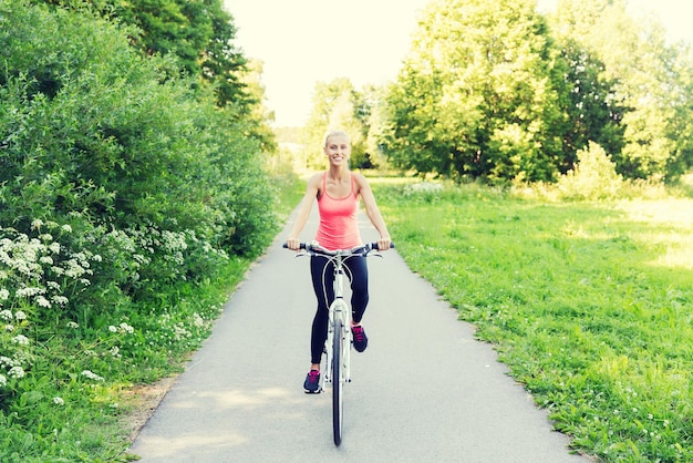 fitness, sport, persone e concetto di stile di vita sano - giovane donna felice in bicicletta all'aperto