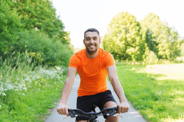 fitness, sport, persone e concetto di stile di vita sano - giovane felice in bicicletta all'aperto