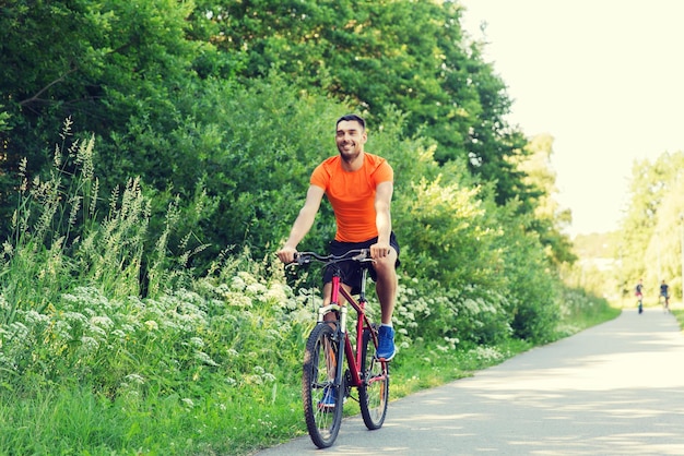 fitness, sport, persone e concetto di stile di vita sano - giovane felice in bicicletta all'aperto