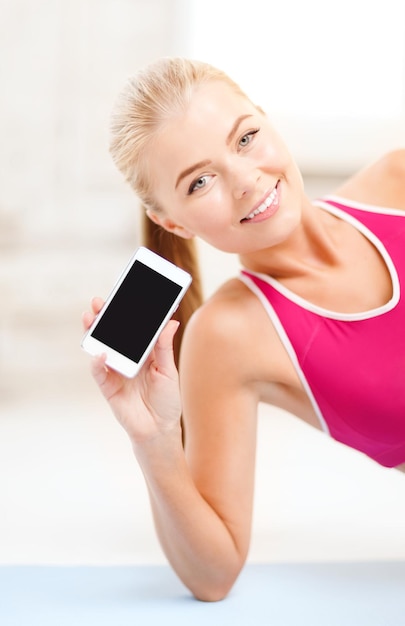 fitness, tecnologia, pubblicità e concetto di esercizio - donna sorridente sdraiata sul pavimento e semina schermo nero vuoto per smartphone