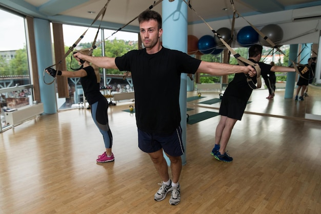 Fitness Trx Cinghie di sospensione Esercizi di allenamento Donne e uomini che lavorano con il proprio peso in palestra