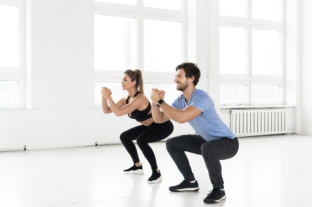 Fitness uomo e donna durante l'allenamento con in palestra. Esercizio di squat per i muscoli di glutei e fianchi.