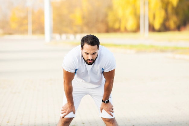 Fitness. Uomo stanco corridore riposo dopo aver eseguito su stree della città