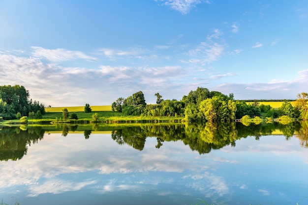 Fiume calmo in primavera all'alba con il riflesso del bel cielo