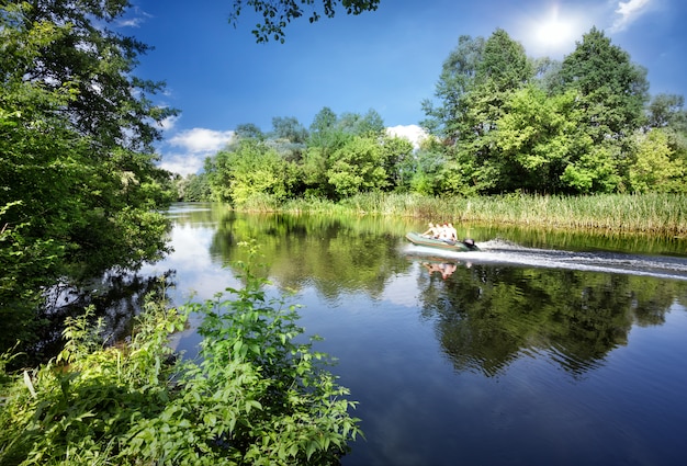 Fiume con una barca a motore e alberi verdi sulla riva