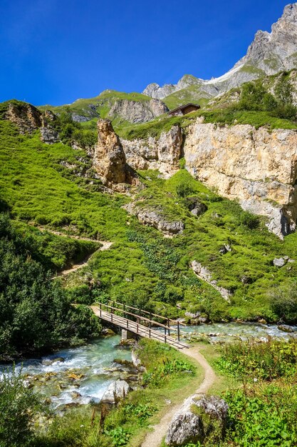 Fiume di montagna e ponte di legno nella valle alpina della Vanoise