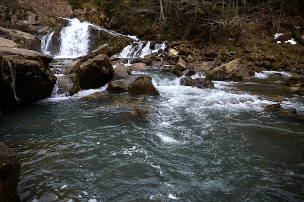 Fiume di montagna rocce strette e formando cascate Zona rurale del villaggio ucraino in montagna All'inizio della primavera nei Carpazi