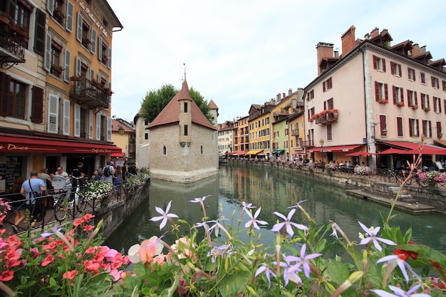 Fiume Thiou con il palazzo medievale di Annecy e fiori in primo piano.