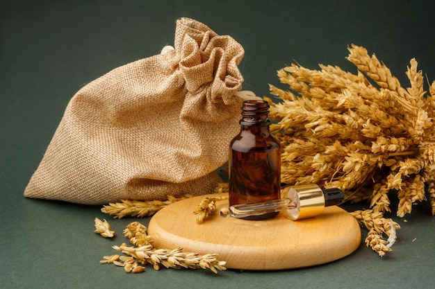 Flacone contagocce con estratto di grano vicino a spighe di grano su sfondo bianco Concetto di cosmetici Ecobio