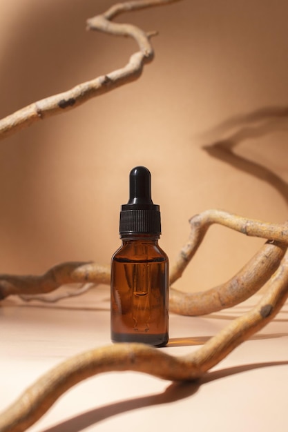 Flacone contagocce in vetro con supporto per olio essenziale o siero cosmetico su sfondo pastello con albero di ramo Prodotti omeopatici a base di erbe Cosmetici termali organici naturali