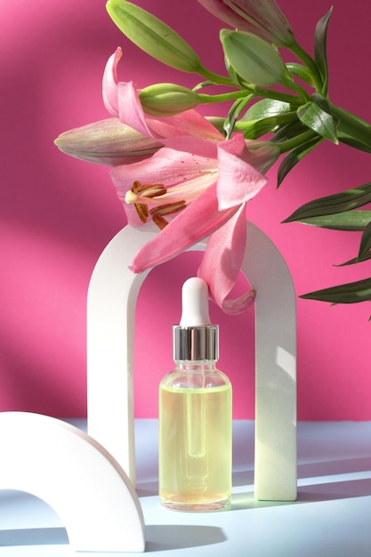 Flacone cosmetico ad arco con fiore di giglio e ombra su sfondo rosa Concetto di spa per la cura del viso e del corpo Siero all'olio di acido ialuronico con prodotto per la cura della pelle di collagene e peptidi