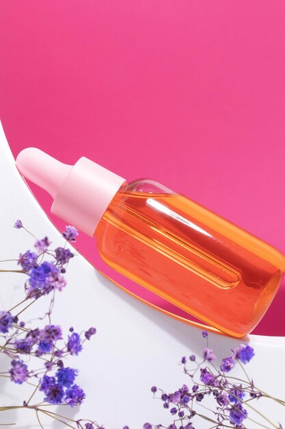 Flacone cosmetico in vetro con olio o siero per la cura della pelle su un podio speciale su sfondo rosa