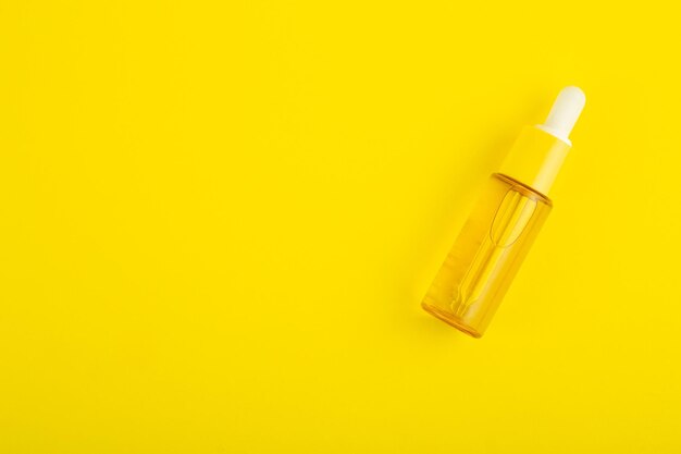 Flacone in vetro giallo con pipetta con olio essenziale su sfondo giallo vista dall'alto Cosmetico aromatico