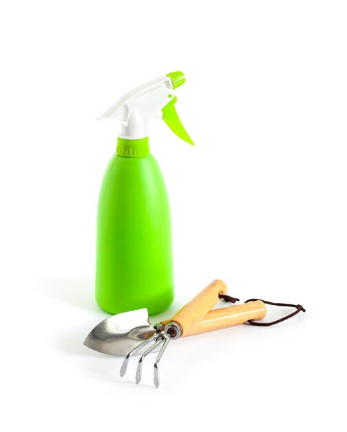 Flacone spray verde e attrezzi da giardino su sfondo bianco. Concetto di cura delle piante.