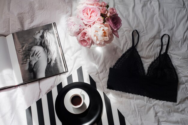 Flat lay con lingerie di pizzo, bouquet di rose, caffè e rivista