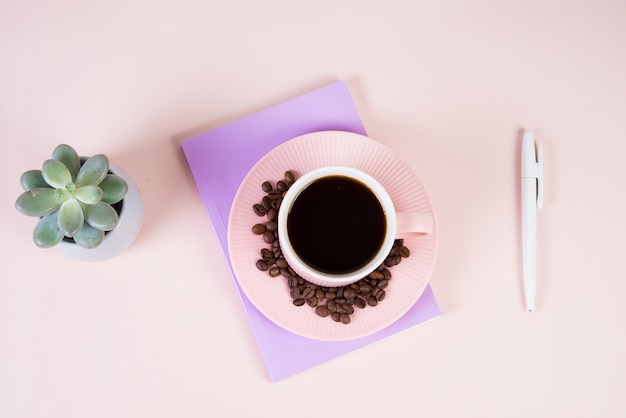 Flatlay con una tazza di caffè nero sul tavolo, un blocco note e una succulenta in una pentola di ceramica. Desktop, business, colori pastello
