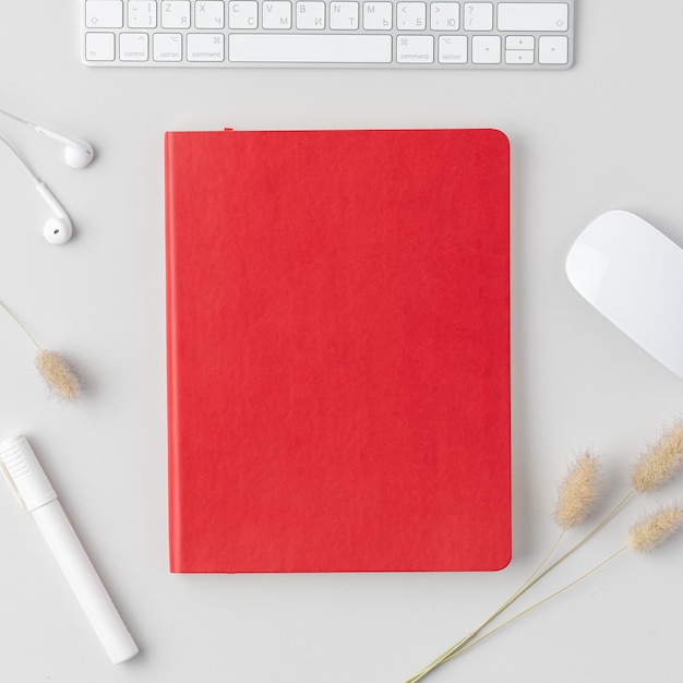 Flatlay del tavolo della scrivania dell'ufficio domestico Vista dall'alto dell'area di lavoro con le cuffie verdi dell'indicatore del mouse della tastiera del notebook e fiori secchi su sfondo bianco