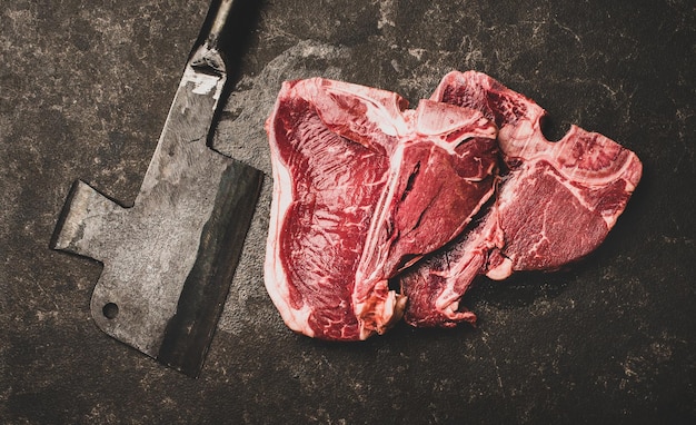 Flatlay di bistecche di manzo fresche con l'osso e composizione ampia mannaia