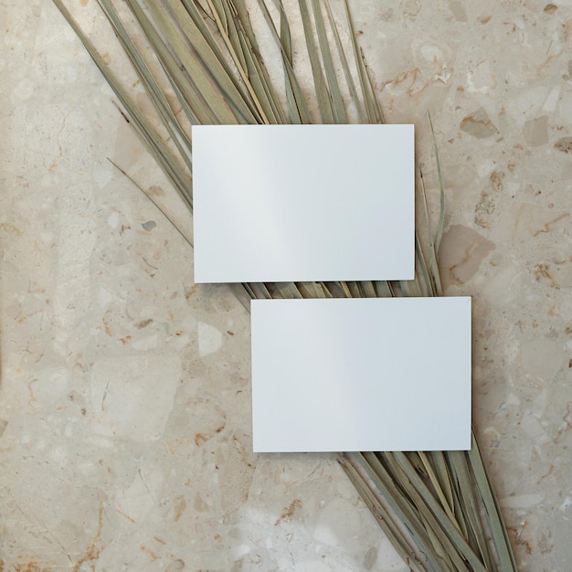Flatlay di carte di carta bianche gambo di foglia di palma secca su sfondo di marmo modello aziendale vista superiore flat lay minimalista estetico lusso bohémien concetto di branding aziendale