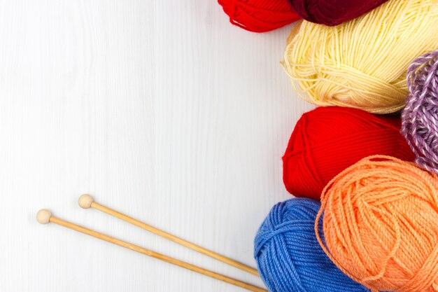 Flatlay di multicolore pastello tricottare matasse di filati e ferri da maglia su sfondo bianco