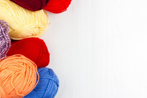 Flatlay di multicolore pastello tricottare matasse di filati e ferri da maglia su sfondo bianco