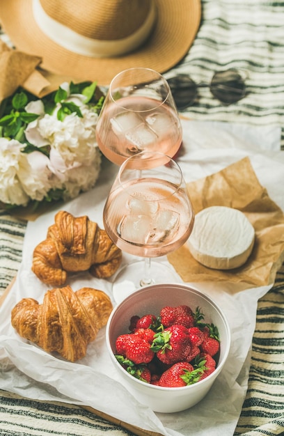 Flatlay di vino rosato fragole croissant brie formaggio a bordo