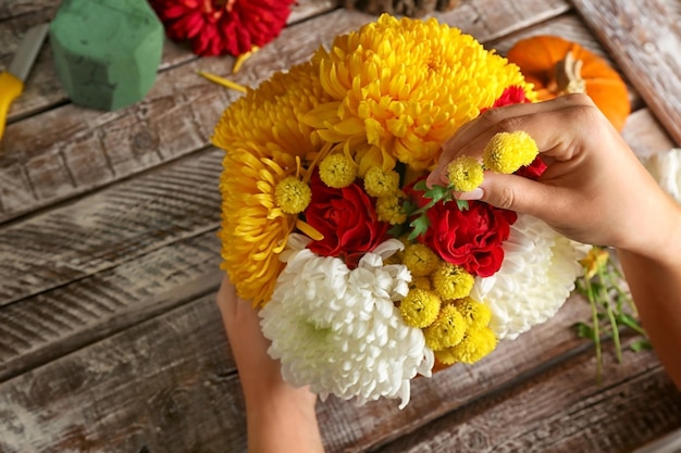 Florista al lavoro Decorazione della casa con zucca e fiori su sfondo di legno