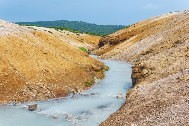 Flusso di idrogeno solforato caldo tra le rive di cenere vulcanica e tefra nella caldera del vulcano Golovnin isola di Kunashir