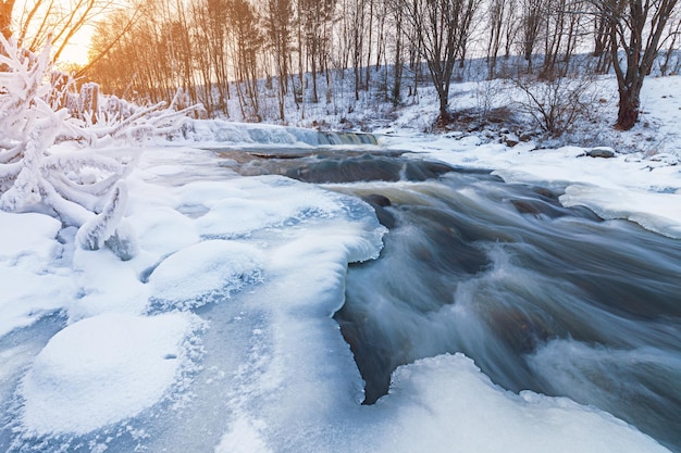 Flusso invernale racchiuso nel ghiaccio con una spolverata di neve e brina