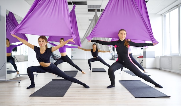 Fly yoga, formazione di gruppo femminile con amache. Mix di esercizi di fitness, pilates e danza. Donne sull'allenamento yogi in studio sportivo