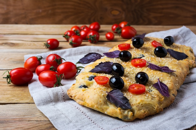 Focaccia con olive, pomodorini e foglie di basilico