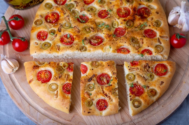 Focaccia con pomodori e olive. Pane Italiano Tradizionale. Cottura fatta in casa. Primo piano, messa a fuoco selettiva.