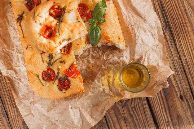 Focaccia con pomodorini e basilico al rosmarino su legno Sulla carta marrone beige