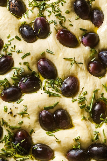 Focaccia cruda con uve rosse su un tavolo blu in una teglia pronta per la cottura Cucina italiana