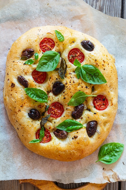 Focaccia di focaccia fresca italiana con pomodori, olive, aglio ed erbe aromatiche.