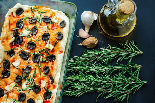 Focaccia domestica con olive e rosmarino su un tavolo nero